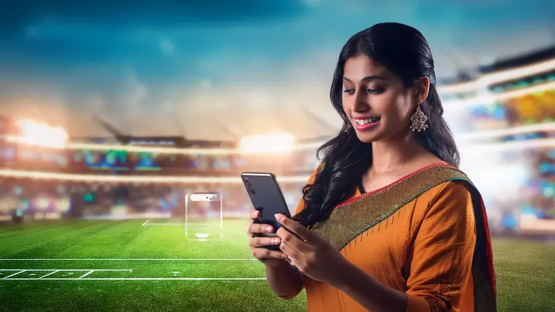 A player checking match markets on a phone at a ground.